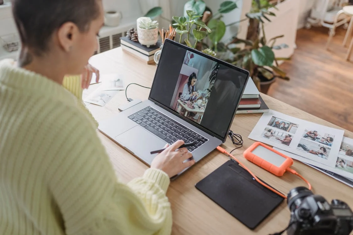 Une personne devant son écran d'ordinateur regarde des photos qu'elle a prise.